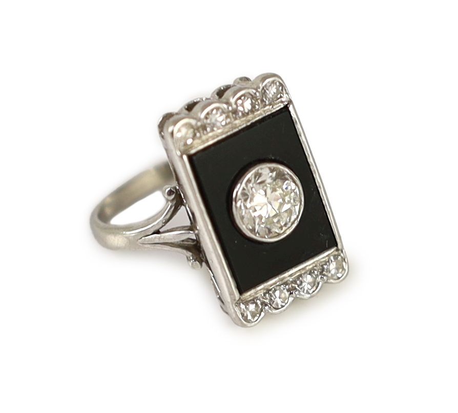 A platinum, single stone diamond and black onyx set rectangular tablet ring, with eight stone diamond setting